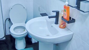 A bathroom with a toilet, sink, and mirror. - Tranquil 3-bedroom apartment with AC in Dar es Salaam (Dar es Salaam)