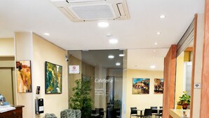 Vestíbulo de hotel con mostrador de recepción, zona de estar y un letrero que indica una cafetería.