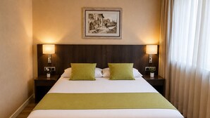 Habitación de hotel con una cama grande, dos lámparas de noche, un cuadro en la pared y una ventana con cortinas.