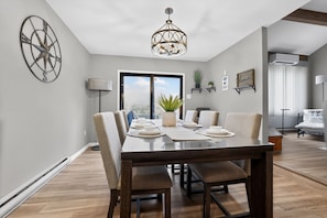 A dining area with a wooden table, chairs, a chandelier, and a large window with a view. - Mystic Escape + Pool Passes Near Big Boulder (Lake Harmony)