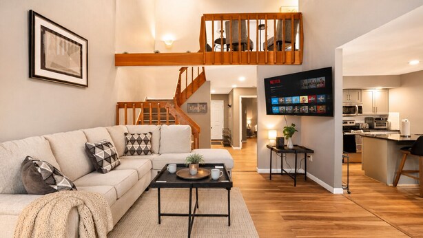 Ein modernes Wohnzimmer mit einer Couch, einem Couchtisch und einer Treppe, die in einen oberen Bereich führt.