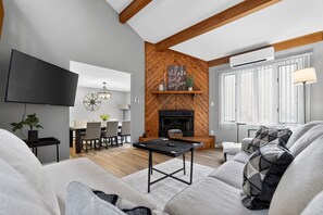 A modern living room with a fireplace, a flat-screen TV, and a dining area. - Mystic Escape + Pool Passes Near Big Boulder (Lake Harmony)