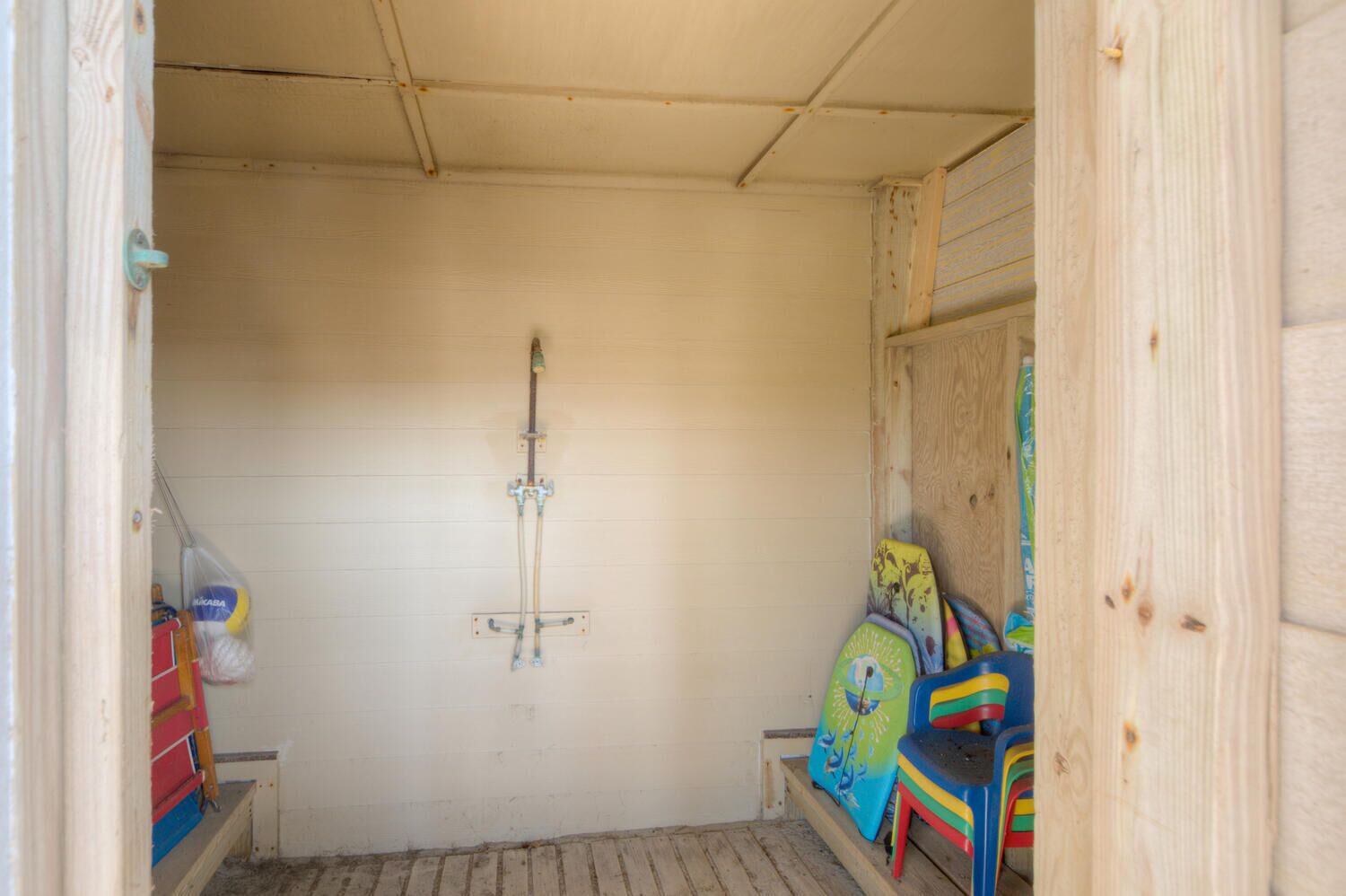 Ein kleiner, abgeschlossener Raum mit Dusche, einer Sitzbank und bunten Kinderstühlen.