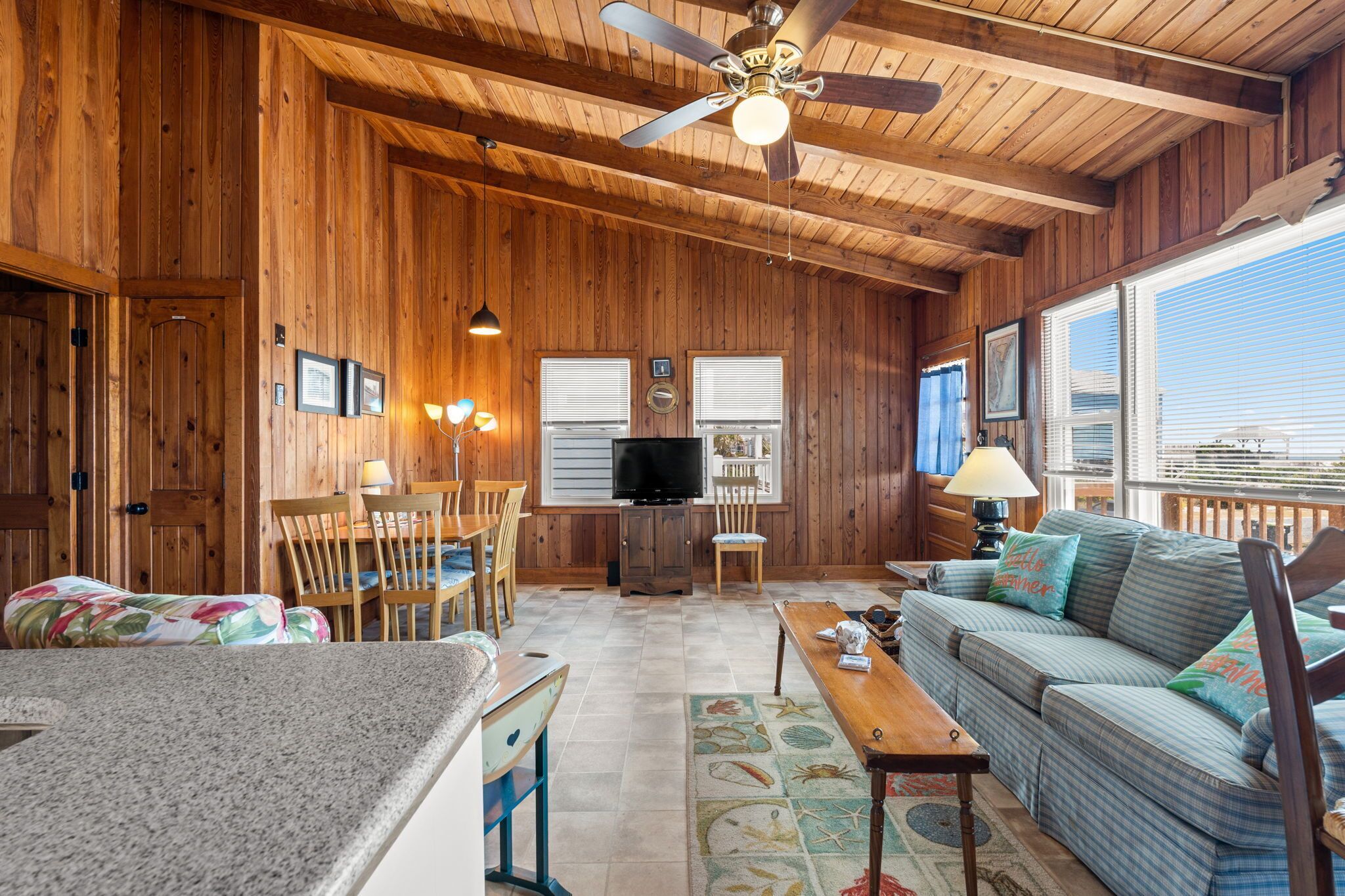 Un intérieur en bois avec un ventilateur de plafond, un téléviseur, un canapé et un coin repas.