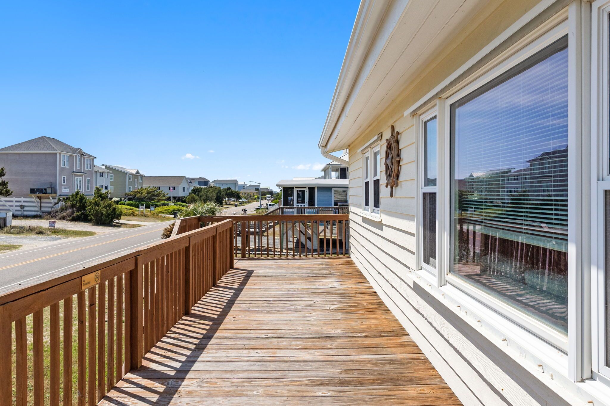 A wooden deck leading to a building with large windows and a ship wheel decoration.