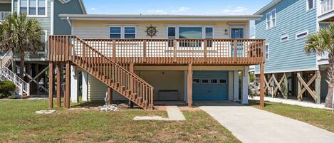 A two-story house with a wooden deck, a garage, and a front yard.