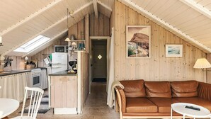 A cozy attic-style room with a kitchen, a brown leather couch, and a dining area. - 5 Person Holiday Home in Nakskov (Nakskov)