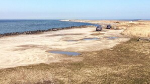 A coastal road with two cars parked on the side, leading to a beach. - 5 Person Holiday Home in Nakskov (Nakskov)