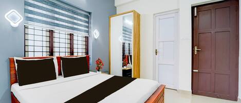 A bedroom with a bed, a wardrobe, a door, and a window with blinds.