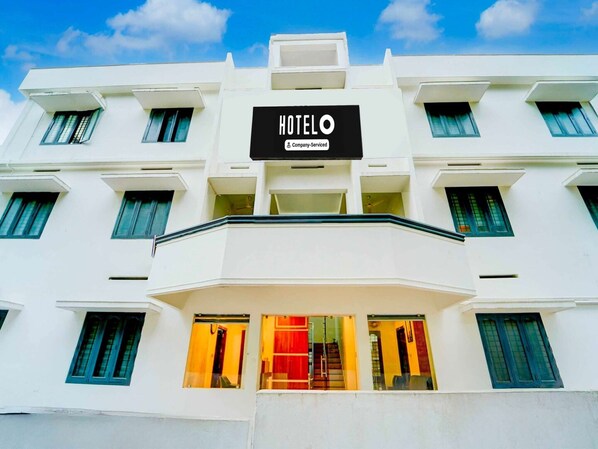 Un edificio de hotel con un llamativo letrero que dice 'HOTEL', varias ventanas y un balcón.