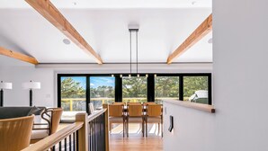 Ein modernes Interieur mit Holzbalken, einer Treppe und einem Essbereich mit Stühlen und Tischen.