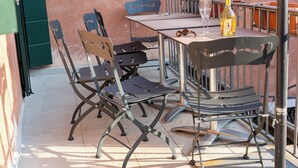 Un patio al aire libre con una mesa, sillas y una botella de vino.