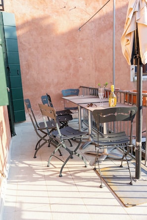 An outdoor patio with a table, chairs, and a bottle of wine. - Historic Palace with Private Terrace | Grand Views over Campo Santo Stefano (Venezia)