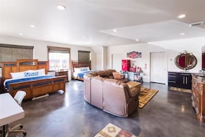 Una habitación amplia con cama, sofá, escritorio y kitchenette.