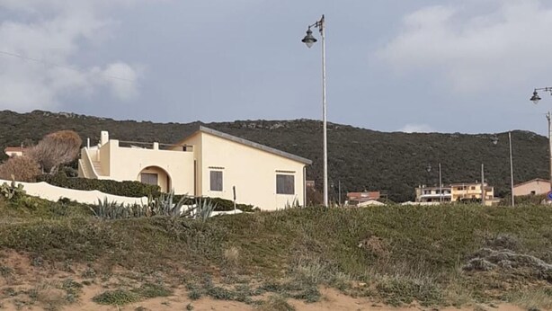 Ein sandiger Strand mit einem eingeschossigen Gebäude, das ein flaches Dach und eine kleine Veranda hat.