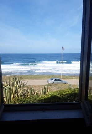 A view of the ocean through a window, with waves crashing onto the shore. - House by the sea - just a few steps to the beach, with garden & terrace (Porto Alabe)