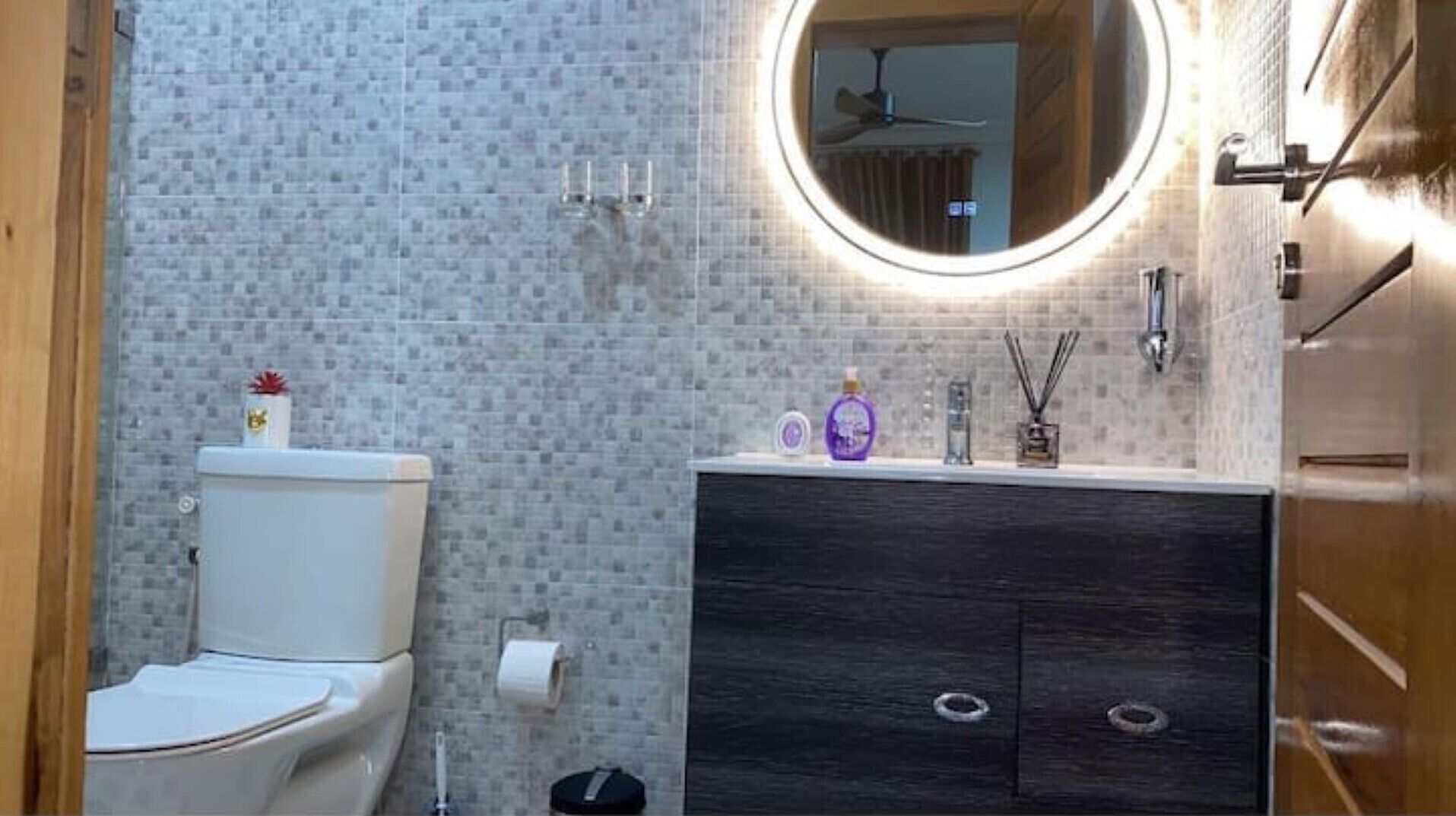 A bathroom with a toilet, a vanity with a mirror, and a shower area.
