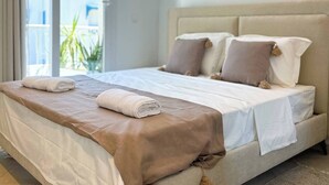 A hotel room with a bed, pillows, and a view through the window.