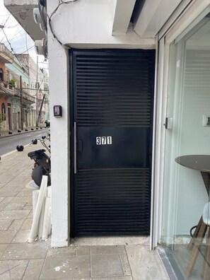 A closed black door with the number 3711, a white wall, and a street view with buildings and parked scooters. - Modern Zona Colonial Apartment  Walkable & Cozy (Santo Domingo)