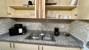 Une cuisine dotée d’un plan de travail en granit, d’un évier en acier inoxydable et d’une machine à café.