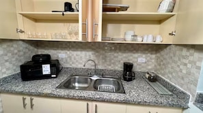 A kitchen with a granite countertop, stainless steel sink, and a coffee maker. - Modern Zona Colonial Apartment  Walkable & Cozy (Santo Domingo)