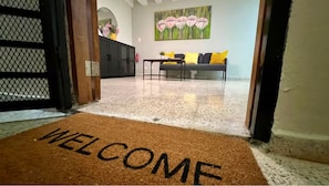 A hallway with a welcome mat, a sofa, a table, and a painting on the wall. - Modern Zona Colonial Apartment  Walkable & Cozy (Santo Domingo)