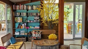 A cozy reading area with bookshelves, a bench, and round tables. - ZEcamping 3* pataugeoire piscine chalet 31m2 6 pers (Saint-Projet)