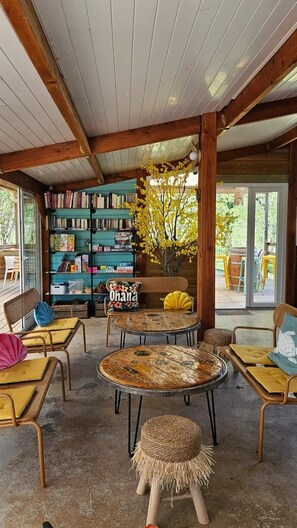 Un coin lecture confortable avec des étagères à livres, un banc et des tables rondes.