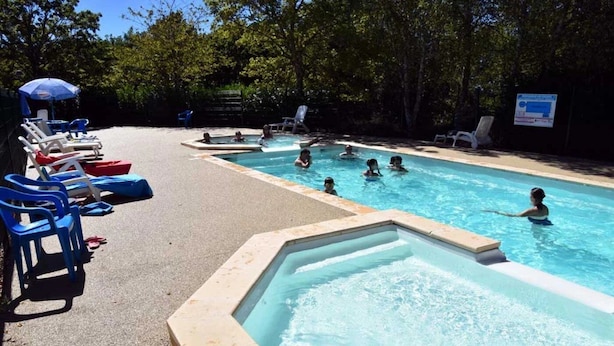 A swimming pool with multiple lanes, lounge chairs, and a shaded area with an umbrella. - ZEcamping 3* familial pataugeoire dog friendly locatif LV BBQ 40m2 (La Souterraine)