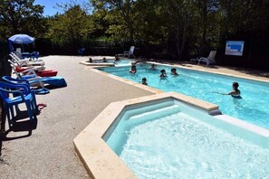 A swimming pool with multiple lanes, lounge chairs, and a shaded area with an umbrella.