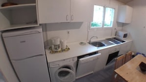 A compact kitchen with a washing machine, a sink, and a microwave. - ZEcamping 3* familial pataugeoire dog friendly locatif LV BBQ 40m2 (La Souterraine)