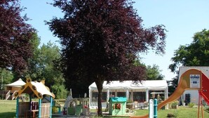 Ein Spielplatz mit Spielgeräten, einer überdachten Sitzgelegenheit und einer Rutsche.