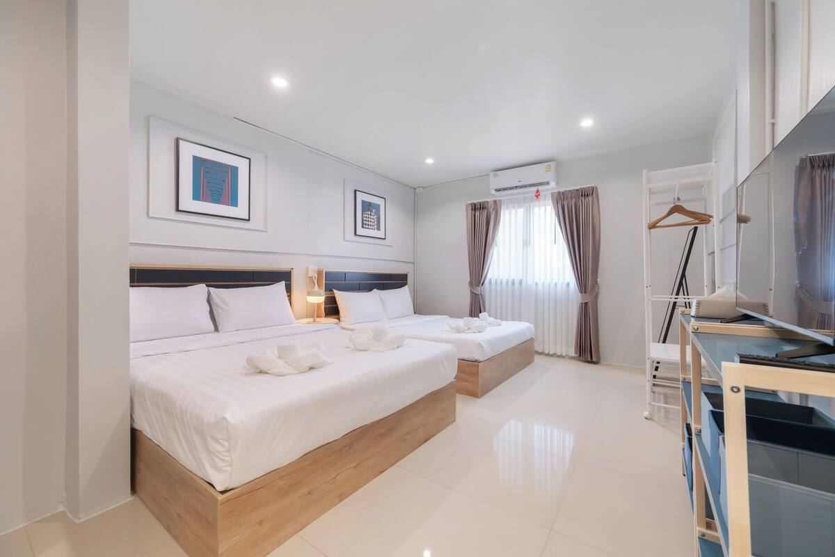 Habitación de hotel con dos camas, un escritorio, un armario y aire acondicionado.