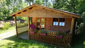 A wooden cabin with a porch, windows, and a wooden fence.