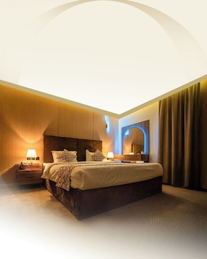 Een hotelkamer met een groot bed, nachtkastjes, een spiegel en een plafondlamp.