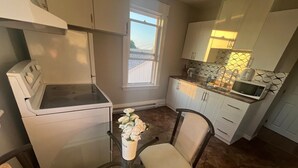 A compact kitchen with a microwave, a small table with chairs, and a window providing natural light.