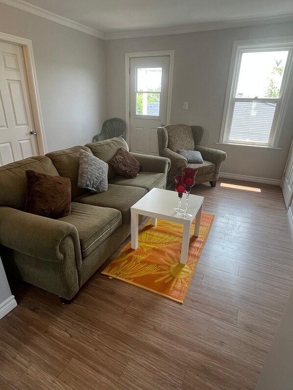 Un salon comprenant un canapé, un fauteuil et une petite table sur laquelle est posé un vase.