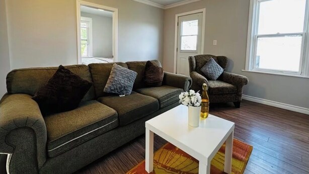 A living room with a sectional sofa, a white coffee table, and two armchairs.