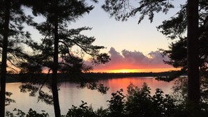 Un atardecer sobre un lago tranquilo con árboles enmarcando la vista.