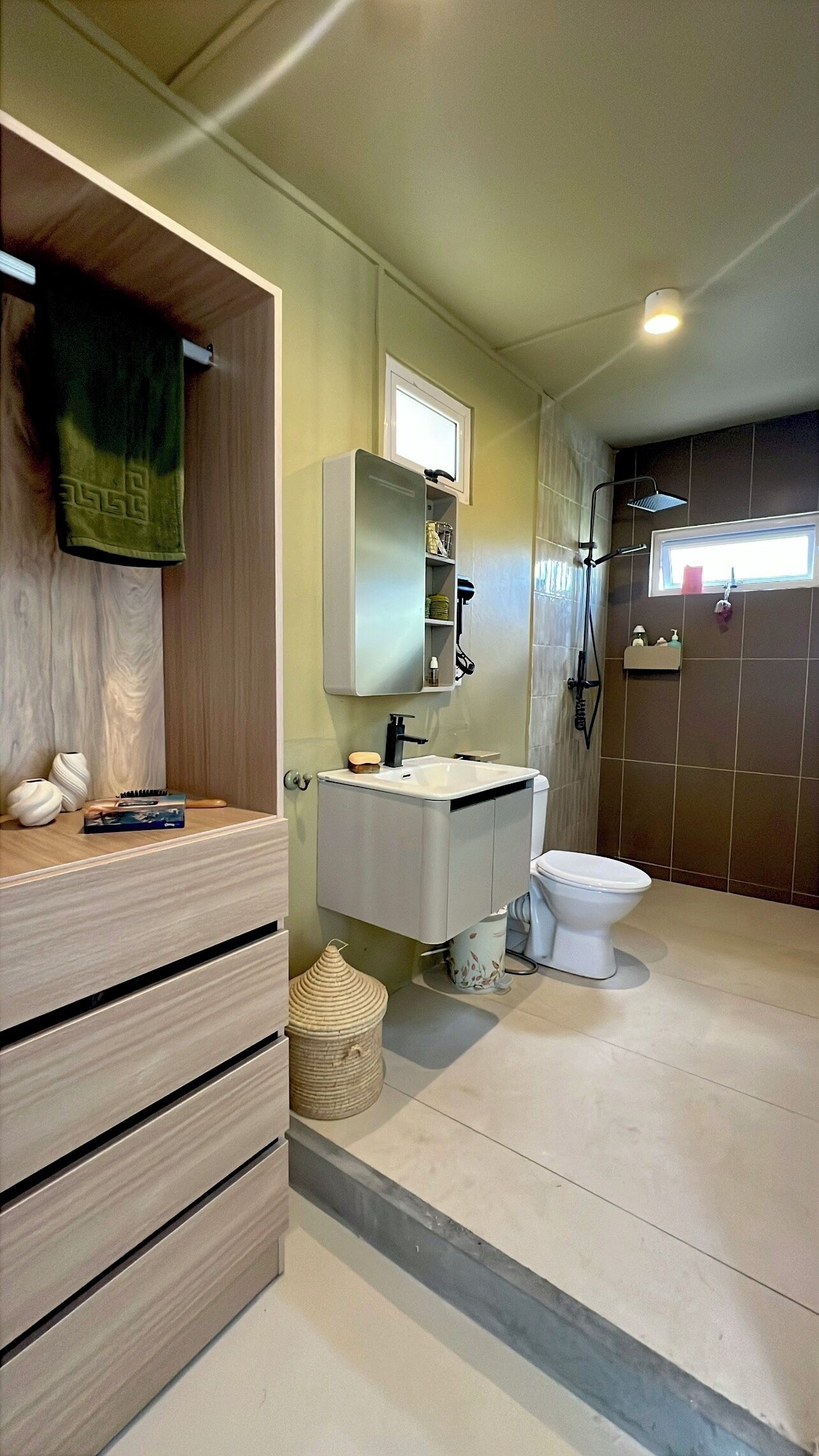 Une salle de bain avec un meuble-lavabo en bois, un évier, des toilettes et un espace douche.