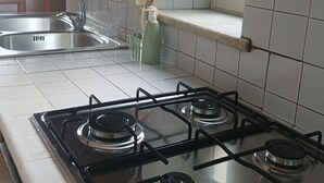 Een keuken met een gasfornuis, een spoelbak en een raam.