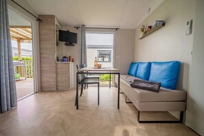 Moderni olohuone, jossa on sohva, ruokapöytä ja televisio.