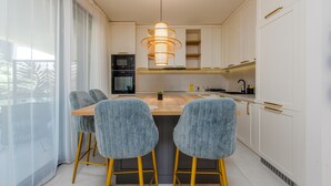 Una cocina moderna con armarios blancos, una isla central y taburetes de bar.