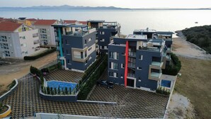 Un moderno complejo de apartamentos con varios edificios, piscina en la azotea y vistas al mar.