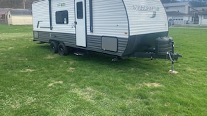 Una caravana StarCraft aparcada sobre gespa, amb una porta que porta la inscripció 'AR ONE' i una finestra visible.