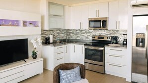 Una cocina moderna con armarios blancos, un microondas, una estufa y un refrigerador.