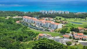 Un resort costero con varias edificaciones, un campo de golf y vista al océano.