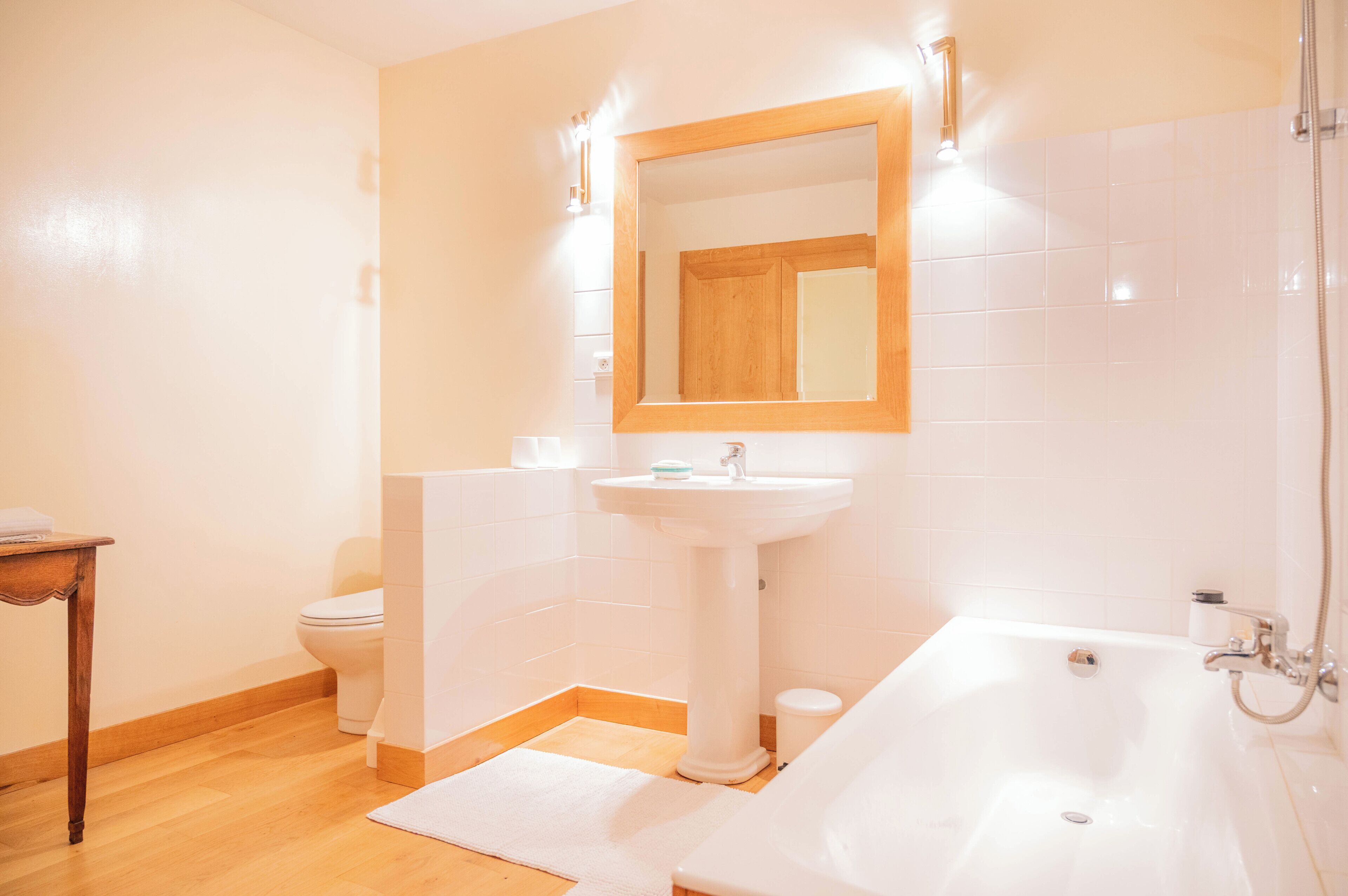 Un baño con lavamanos pedestal, espejo, inodoro y bañera.
