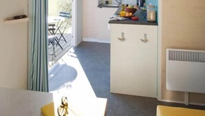 A compact kitchen with a dining area, a small table, and a chair. - Camping 3 étoiles - Piscine  - ccbfgbf (Collias)