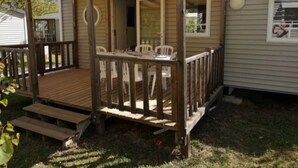 Une terrasse en bois avec un espace salon couvert, une petite table et des chaises.